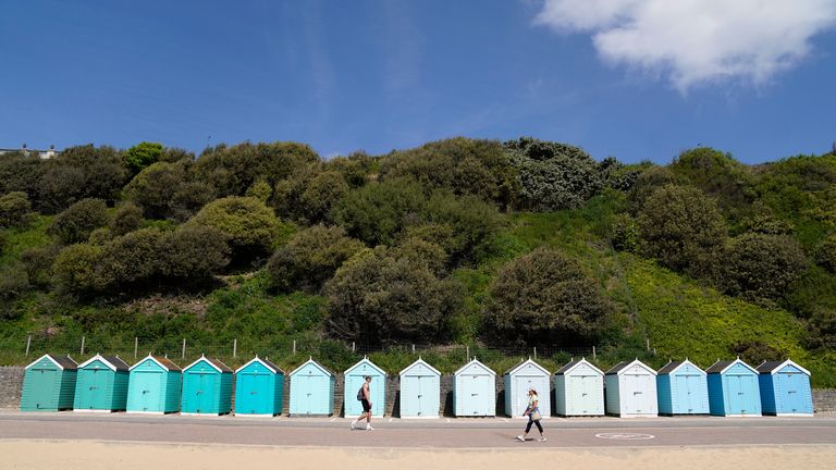 People make their way past beach huts on Bournemouth beach in Dorset