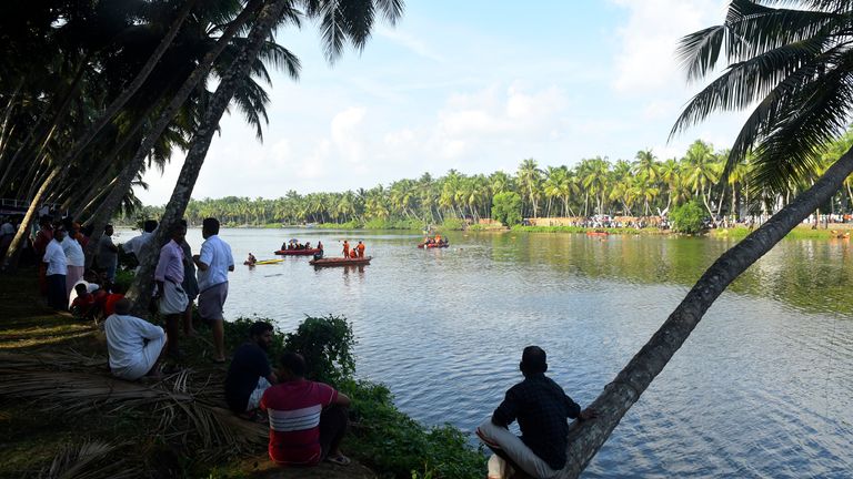 People watch rescuers  search a river after a tourist boat capsized Sunday night in Malappuram, Kerala, India, Monday, May 8, 2013. More than a dozen were killed. (AP Photo/P.P. Afthab)