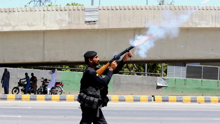 A police officer fires tear gas to disperse supporters of Khan in Peshawar. Pic: AP