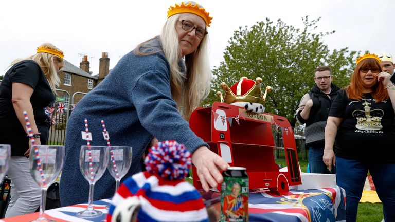 A woman places a beer can with the picture of Britain&#39;s King Charles on it, as she sets up a table during a picnic at Windsor Castle, in Windsor, Britain May 7, 2023. REUTERS/Stephanie Lecocq..