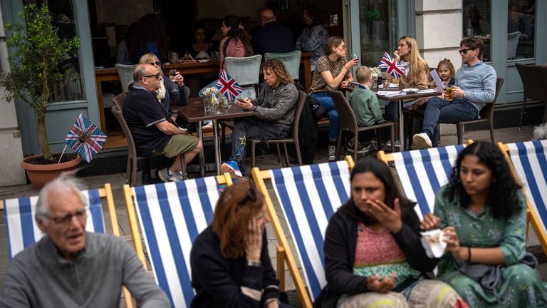People sit at a restaurant and in deckchairs in the street, to eat their lunch as part of the Big Lunch celebration in London
Pic:AP