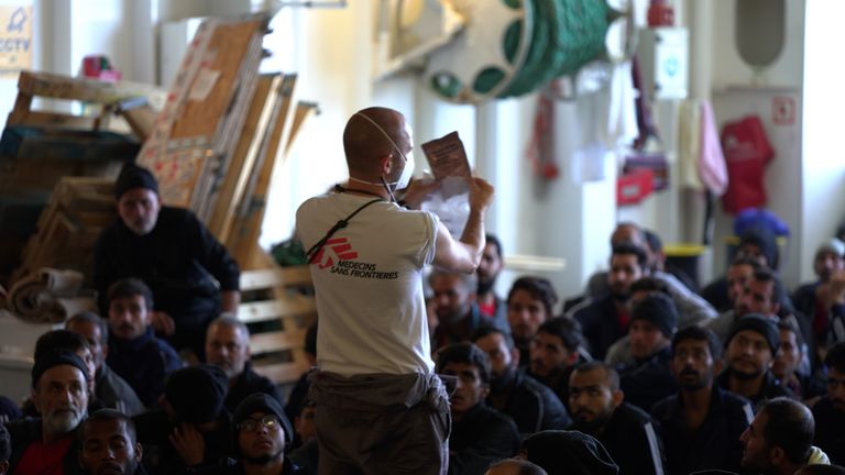 A member of MSF demonstrates to rescued migrants how to prepare MRE ( Meal Ready to Eat ) rations.