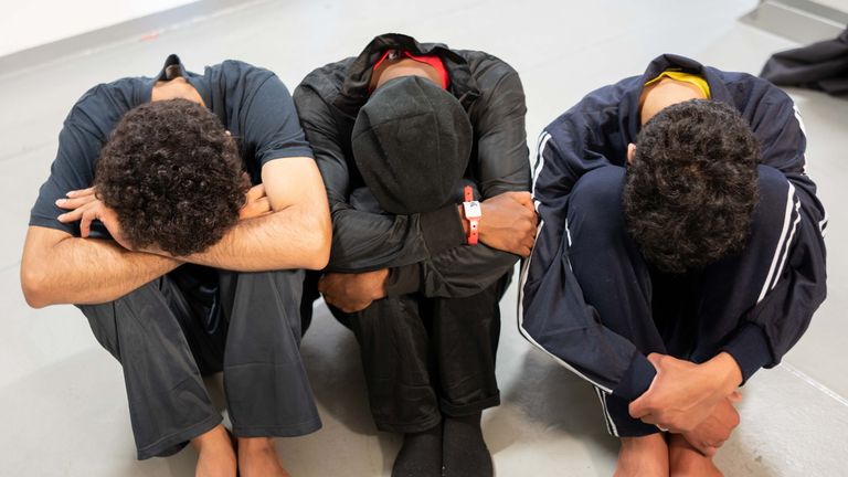 Three migrants demonstrate how they had to sit for days in the fishing vessel that was converted into an migrant transport for all the people to fit in. 