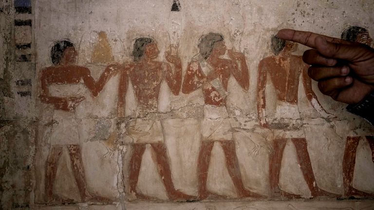 An Egyptian archaeologist points at a coloured painting showing offering sacrifices at a recently uncovered tomb. Pic: AP