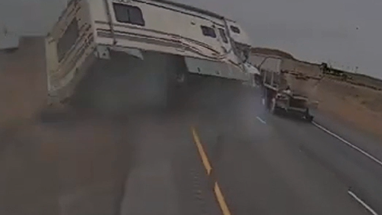 Moment motor home overturns on highway after driver veers into truck.