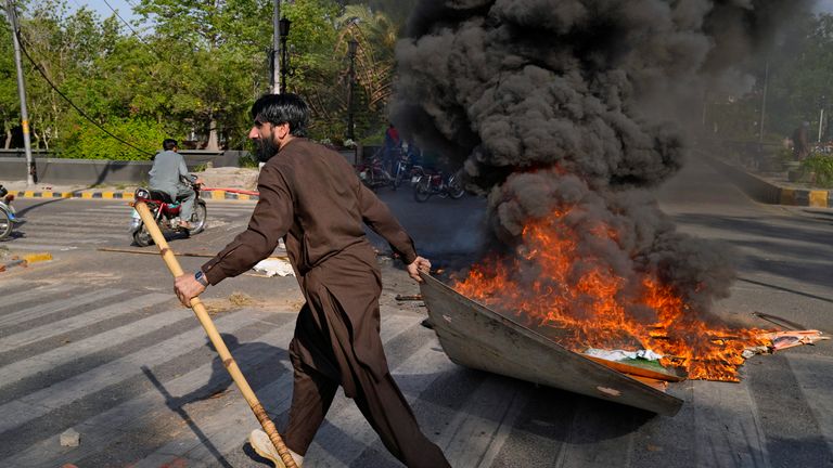 A supporter of Pakistan&#39;s former Prime Minister Imran Khan burns a billboard during a protest against the arrest of their leader, in Lahore, Pakistan, Tuesday, May 9, 2023.  Khan was arrested Tuesday as he appeared in a court in the country...s capital, Islamabad, to face charges in multiple graft cases. Security agents dragged Khan outside and shoved him into an armored car before whisking him away. (AP Photo/K.M.Chaudary)