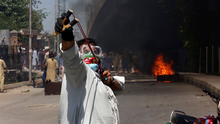 A Khan supporters throws stones using a slingshot toward police officers in Peshawar 