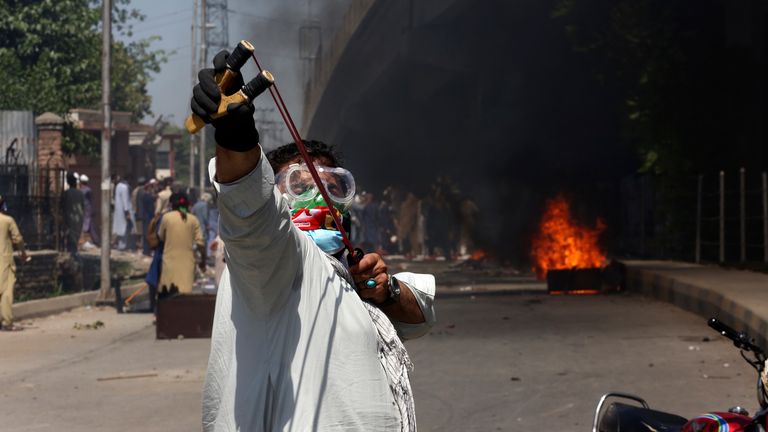 A supporter of Imran Khan throws stones using a slingshot toward police officers during a protest against the arrest of their leader in Peshawar, Pakistan. Pic: AP