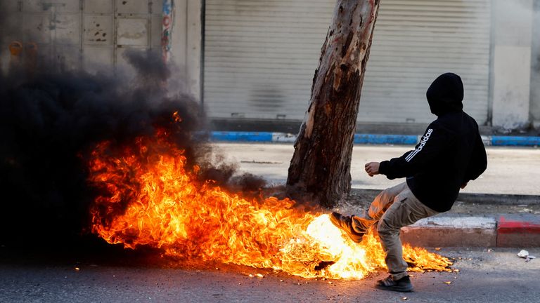A Palestinian kicks a burning object during clashes between Palestinians and Israeli soldiers following the death of Palestinian prisoner Khader Adnan during a hunger strike in an Israeli jail,  