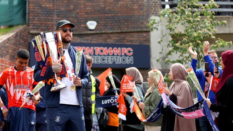 Luton Town&#39;s Sonny Bradley leaves Luton Town&#39;s main reception holding the trophy ahead of an open top bus parade  