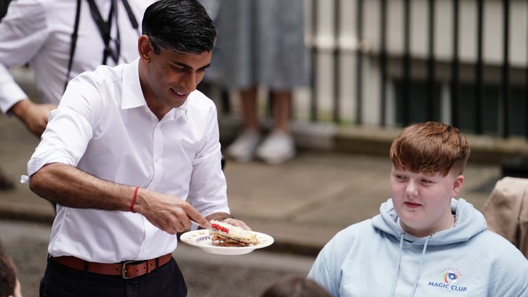Prime Minister Rishi Sunak offers a piece of cake to a guest during a Coronation Big Lunch in Downing Street, London, for volunteers, Ukrainian refugees in the UK, and youth groups. Thousands of people across the country are celebrating the Coronation Big Lunch on Sunday to mark the crowning of King Charles III and Queen Camilla. Picture date: Sunday May 7, 2023.
