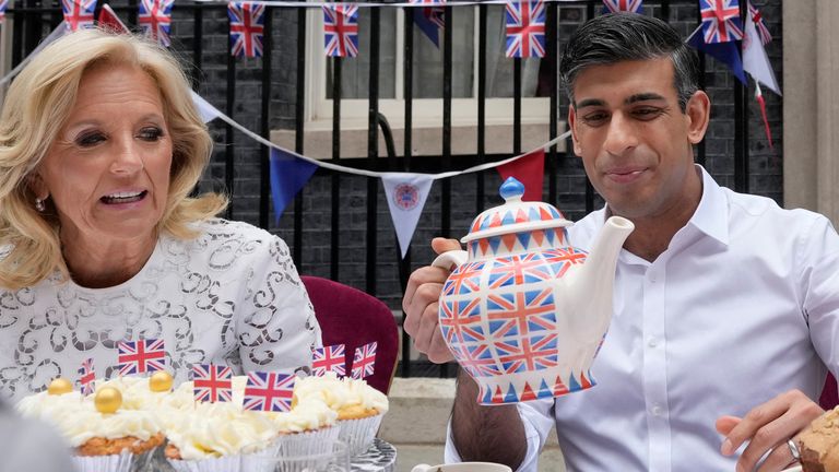 Prime Minister Rishi Sunak holds an oversize tea pot as he goes to pour a cup as he sits next to US First Lady Jill Biden as they attend the Big Lunch party at Downing Street in London Sunday, May 7, 2023. The Big Lunch is part of the weekend of celebrations for the Coronation of King Charles III. Guests at the big lunch include community heroes and Ukrainians displaced by the war, and youth groups. Frank Augstein/Pool via REUTERS
