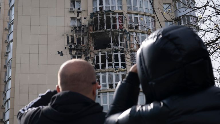People look at a building damaged by a drone that was shot down, during a Russian strike in Kyiv