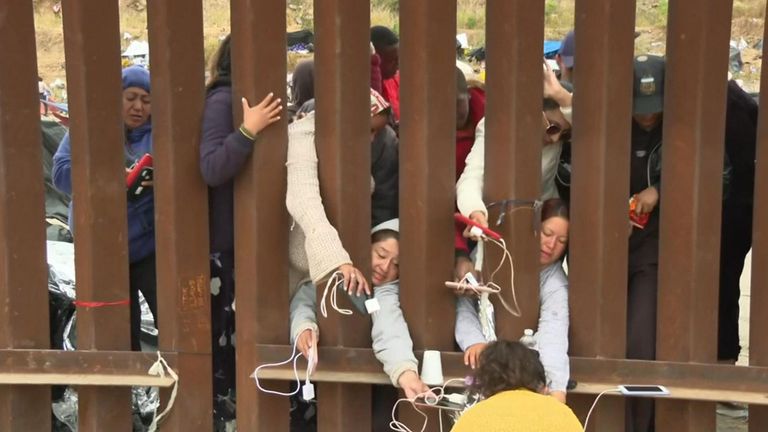 Migrants charge phones at the US-Mexico border