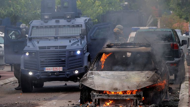 Special police forces officers stand next to a burning car, following clashes between Kosovo police and ethnic Serb protesters, who tried to prevent a newly-elected ethnic Albanian mayor from entering his office, in the town of Zvecan, Kosovo