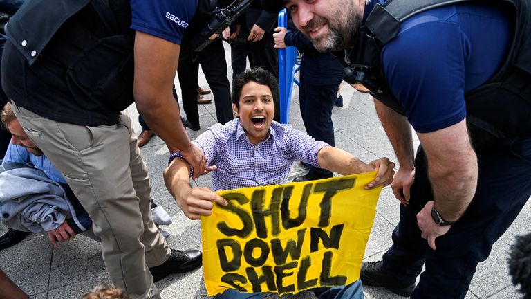 A person holds a sign as security personnel remove protesters during the Fossil Free London demonstration outside the venue of Shell&#39;s annual shareholder meeting, at the ExCeL center, in London, Britain May 23, 2023. REUTERS/Toby Melville
