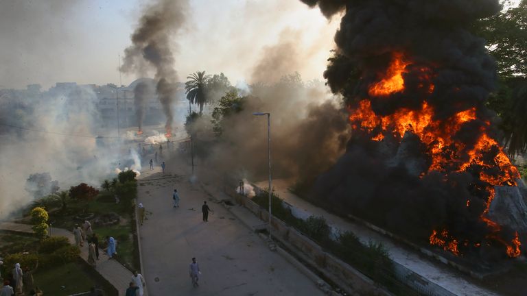 Pakistan'ın Peşaver kentinde, Khan'ın tutuklanmasına karşı düzenlenen bir protesto sırasında polis göz yaşartıcı gazla onları dağıtırken, Pakistan'ın eski Başbakanı İmran Han'ın öfkeli destekçilerinin ateşe verdiği yanan nesnelerden dumanlar çıkıyor Pic:AP