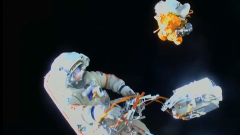 bundle of space junk float away as it gets discarded during spacewalk.