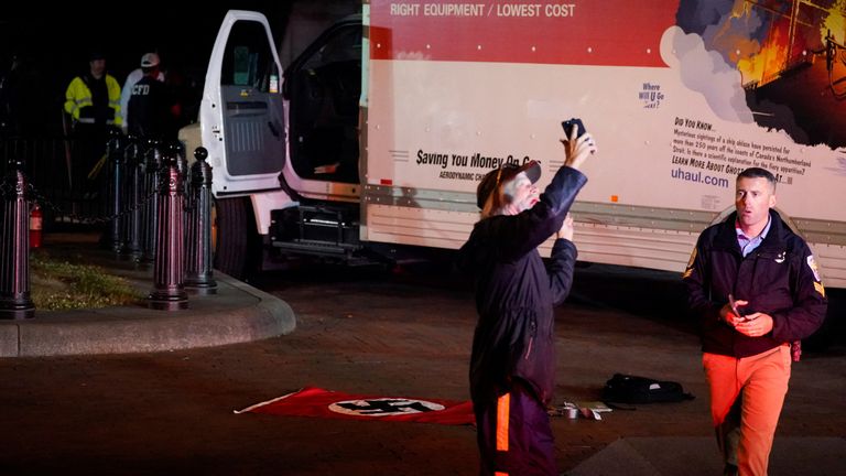 A bystander taking a selfie near a rented box truck is moved away by a U.S. Secret Service agent as law enforcement agencies investigate the truck that crashed into security barriers at Lafayette Park across from the White House in Washington 