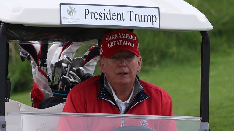 Former US President and Republican presidential candidate Donald Trump rides a golf cart at Trump International Golf Links course, in Doonbeg, Ireland