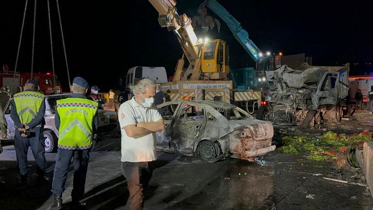 Turkish police officers and emergency personnel work next to burned vehicles after the crash. Pic: AP