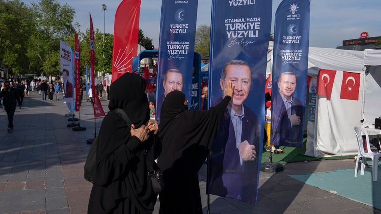A woman gestures in front of a banner with an image of Turkish President and People&#39;s Alliance&#39;s presidential candidate Recep Tayyip Erdogan, in Istanbul