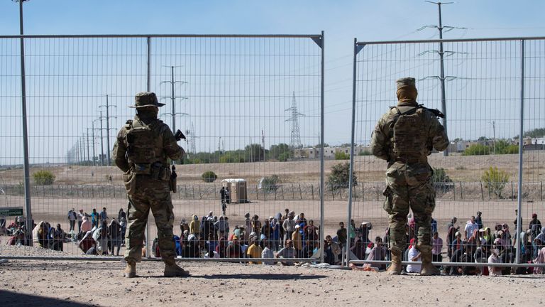 US soldiers watch over a group of migrants waiting near El Paso, Texas, to process their immigration claim as the United States prepares to lift Title 42 restrictions
