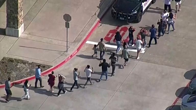 Shoppers walk away with hands raised as law enforcement responds to a shooting at the Allen Premium Outlets in the Dallas area that authorities say left several people injured in Allen, Texas, United States, on May 6, 2023 in a still image from the video.  ABC Affiliate WFAA via REUTERS NO RESALE.  NO ARCHIVE.  MANDATORY CREDIT