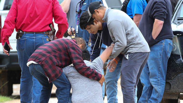 A loved one is consoled by others as he arrives at the scene where five people were shot and killed. Pic: AO