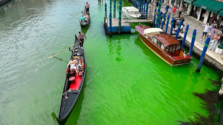 A bright patch of green is seen in the Grand Canal along an embankment lined with restaurants, in Venice, Italy, Sunday, May 28, 2023. Police in Venice are investigating the source of a phosphorescent green liquid patch that appeared Sunday in the city&#39;s famed Grand Canal. (AP Photo/Luigi Costantini)