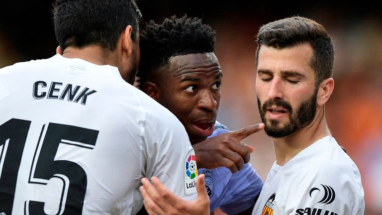 Soccer Football - LaLiga - Valencia v Real Madrid - Mestalla, Valencia, Spain - May 21, 2023 Real Madrid&#39;s Vinicius Junior gestures towards a fan after witnessing abuse as Valencia&#39;s Jose Gaya and Cenk Ozkacar attempt to restrain him REUTERS/Pablo Morano