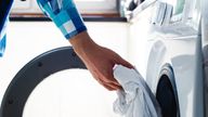 Doing the laundry. Man does the washing in washing machine. (istock)
