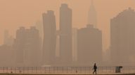 A woman walks along the East River in Long Island as haze and smoke caused by wildfires in Canada hang over the Manhattan skyline, in New York City, New York, U.S., June 7, 2023. REUTERS/Andrew Kelly
