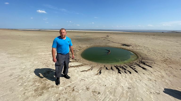 Andriy Starko, pump station engineer, stands next to a pool of water in what was once a full reservoir 


