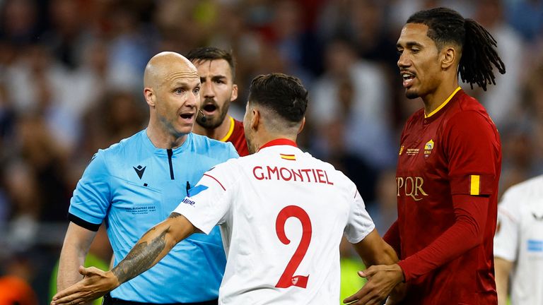 Referee Anthony Taylor talks to Sevilla&#39;s Gonzalo Montiel and AS Roma&#39;s Chris Smalling