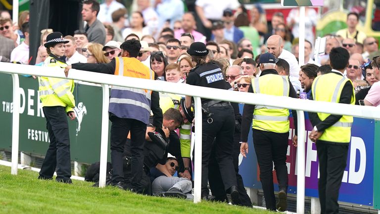 A protestor is escorted off the track by police and stewards during the Betfred Derby during Derby Day of the 2023 Derby Festival at Epsom Downs Racecourse, Epsom. Picture date: Saturday June 3, 2023.