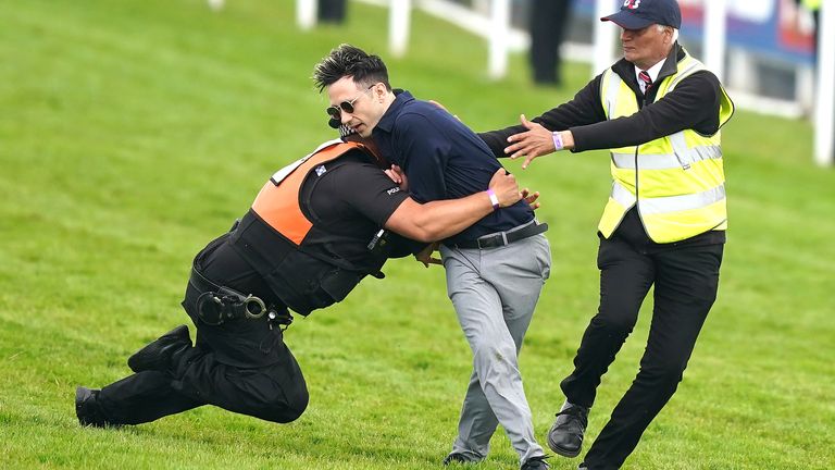 A protestor is tackled by police and stewards prior to the start of the Betfred Derby during Derby Day of the 2023 Derby Festival at Epsom Downs Racecourse, Epsom. Picture date: Saturday June 3, 2023.