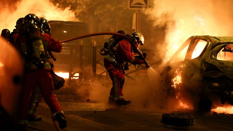 A firefighter extinguishes a burning vehicle during clashes between protesters and police, after the death of Nahel, a 17-year-old teenager killed by a French police officer during a traffic stop, in Nanterre, Paris suburb, France, June 28, 2023. REUTERS/Stephanie Lecocq 