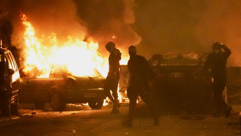 29 Haziran 2023 Perşembe, Paris'in dışındaki Nanterre'de arabalar yanarken gençler polis güçleriyle çatışıyor. Fransa Cumhurbaşkanı Emmanuel Macron, 17 yaşındaki bir teslimat şoförünün trafik kontrolünde polis tarafından öldürüldüğünü anlattı. "affedilmez," ve kapsamlı bir soruşturma yapılması çağrısında bulundu.  Paris'in Nanterre banliyösünde meydana gelen ölüm, bir gecede şiddet olaylarına yol açtı.  (AP Fotoğrafı/Christophe Ena)
