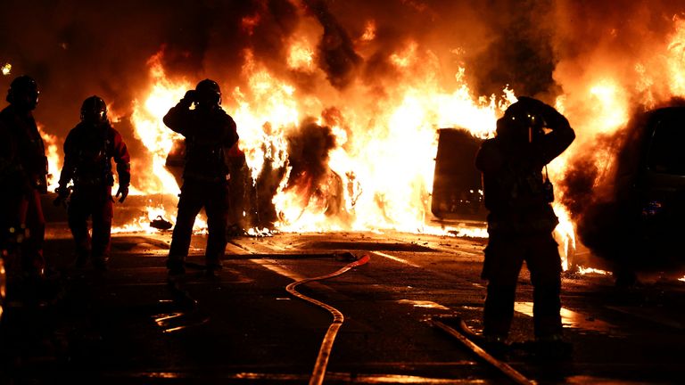 Firefighters surrounded by burning vehicles during clashes between protesters and police in the Paris suburb of Nanterre in France