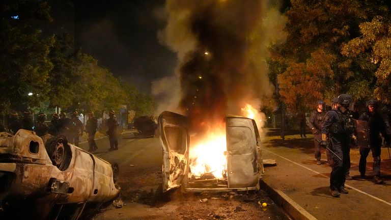 Police forces walk past burning cars in Nanterre, outside Paris. Pic: AP