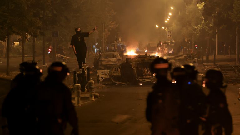 A demonstrator faces off police on the third night of protests sparked by the fatal police shooting of a 17-year-old driver in the Paris suburb of Nanterre, France, Friday, June 30, 2023. The June 27 shooting of the teen, identified as Nahel, triggered urban violence and stirred up tensions between police and young people in housing projects and other neighborhoods. (AP Photo/Aurelien Morissard)