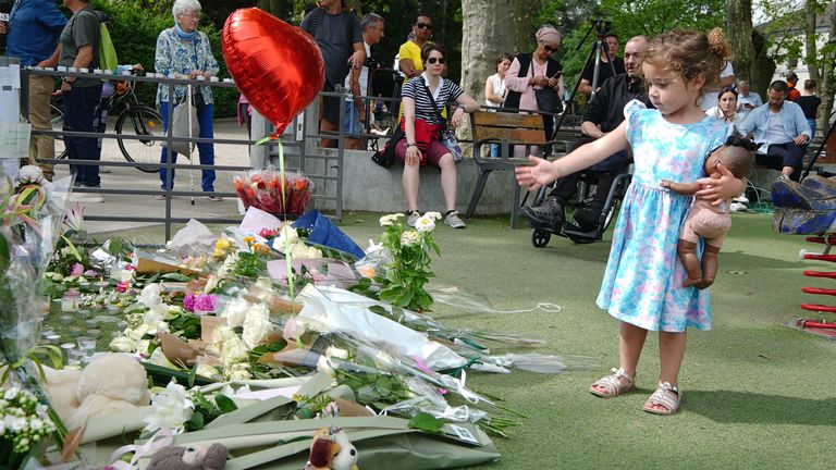 A young child near tributes left near the scene at a lakeside park in Annecy, France, following a knife attack in which a British girl, said to be aged three, was one of four children and two adults wounded when the suspect, identified by police as a 31-year-old Syrian national who has refugee status in Sweden, attacked people with a knife in the town of Annecy on Thursday. The knifeman had been denied asylum in France just days before the attack, according to a minister. Picture date: Friday Ju