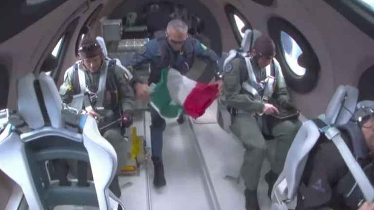 Italian crew members of Galactic 01 unfurling an Italian flag during the zero gravity part of the flight