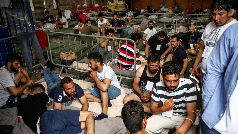 Migrants who were rescued after their boat capsized, are seen inside a warehouse  at the port of Kalamata