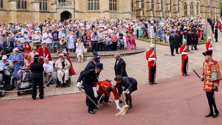 A member of the Household Cavalry faints in position as a Police Officer rushes to his assistance ahead of the the annual Order of the Garter Service at St George&#39;s Chapel, Windsor Castle, Berkshire. Picture date: Monday June 19, 2023.
