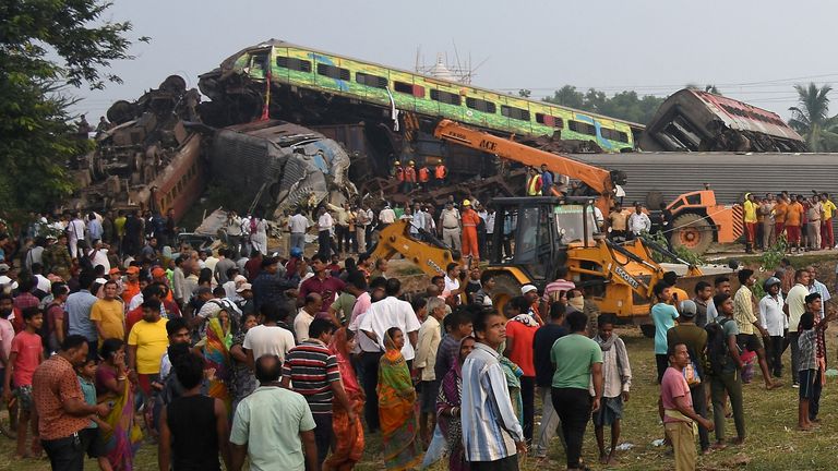 Oamenii stau lângă vagoane avariate după ce două trenuri de pasageri s-au ciocnit în districtul Balasore din statul Odisha, din estul Indiei, 3 iunie 2023. REUTERS/Stringer FĂRĂ VÂNZĂRI.  FĂRĂ ARHIVE.  IMAGINI TPX ALE ZILEI