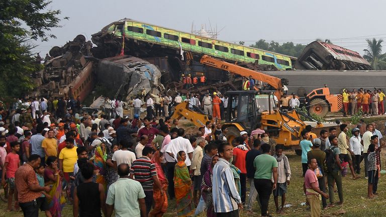 People stand next to damaged coaches after two passenger trains collided in Balasore district in the eastern state of Odisha, India, June 3, 2023. REUTERS/Stringer NO RESALES. NO ARCHIVES. TPX IMAGES OF THE DAY