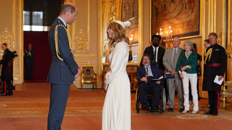 Kate Garraway, from London, is watched by her husband Derek Draper as she is made a Member of the Order of the British Empire by the Prince of Wales at Windsor Castle. The honour recognises services to broadcasting, to journalism and to charity. Picture date: Wednesday June 28, 2023.