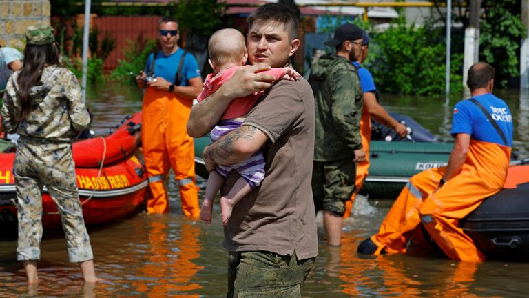 A man carries a child as members of Russia&#39;s emergencies ministry evacuate residents of a flooded area following the collapse of the Nova Kakhovka dam in the course of Russia-Ukraine conflict, in the town of Hola Prystan in the Kherson region, Russian-controlled Ukraine, June 8, 2023. REUTERS/Alexander Ermochenko